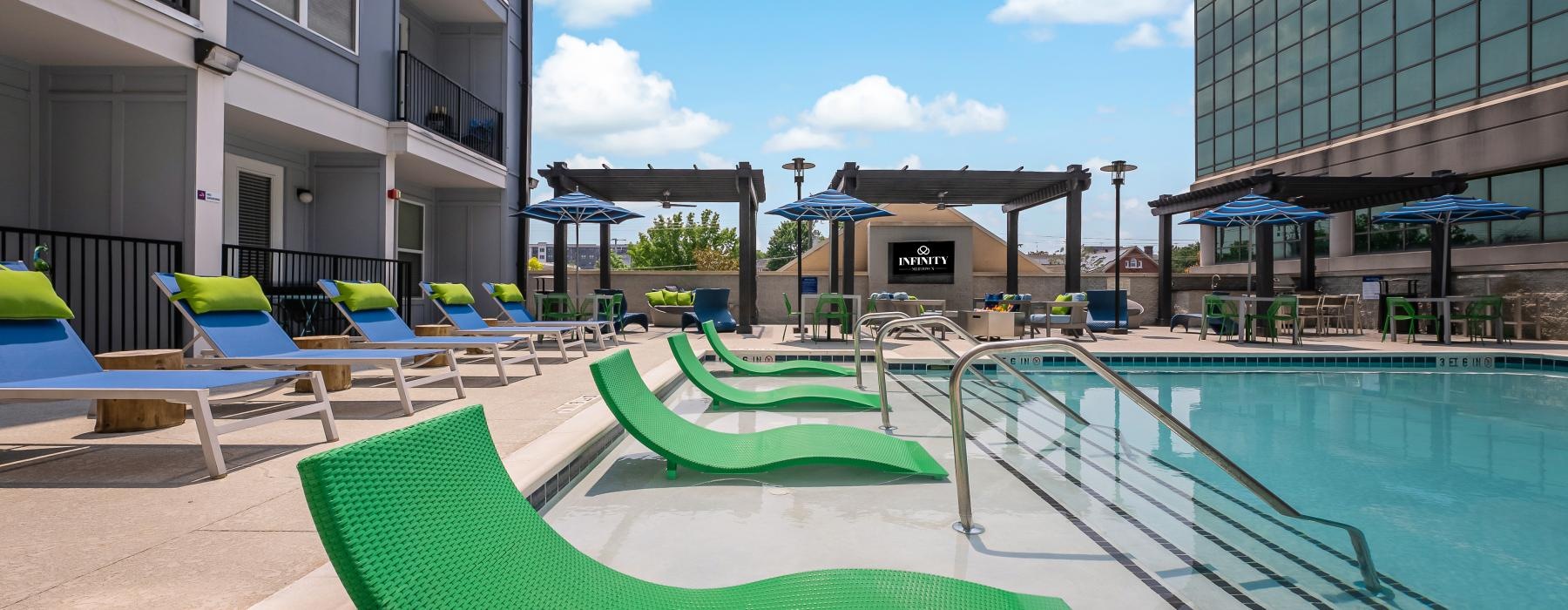 a pool with lounge chairs and tables by it