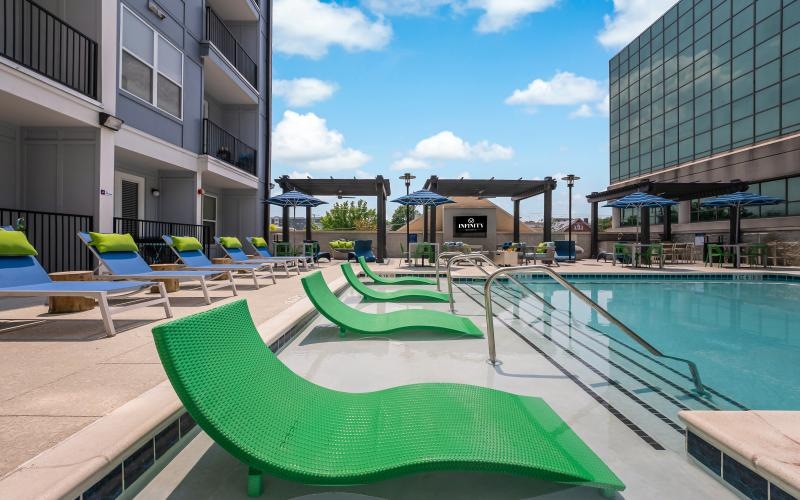 a pool with lounge chairs and tables by it